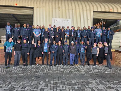 The DLS team in two rows in front of a warehouse with a DETOUR sign.